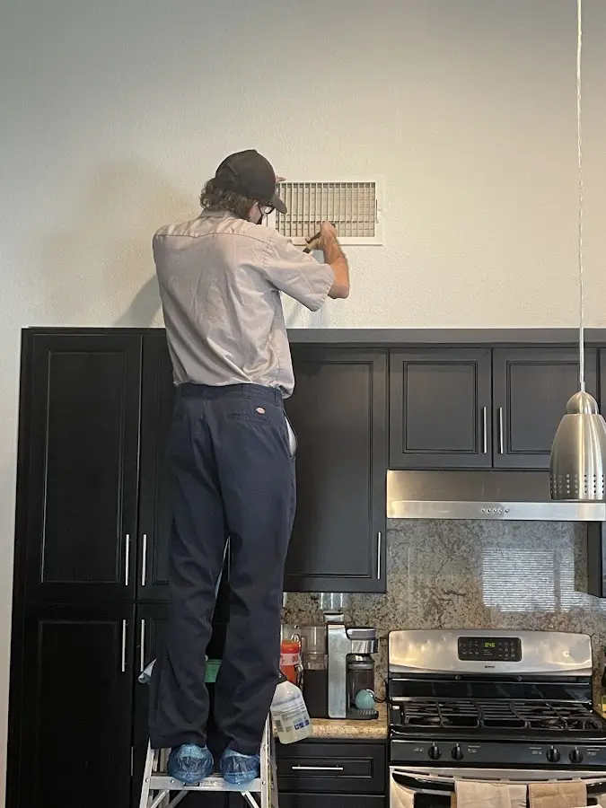 Technician inspecting an air vent during HVAC service in Oxford